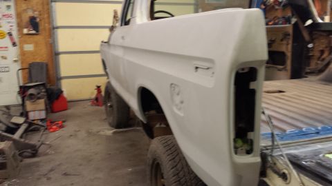 1978 Ford Bronco - Primer-finished pickup truck body, viewed from the rear quarter, showing the missing taillight area.
