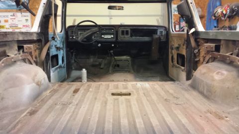 1978 Ford Bronco - The interior of a 1978 Ford Bronco is shown, with the dashboard and steering wheel visible, and the cargo area stripped down.