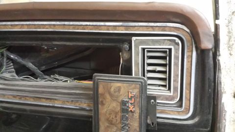 1978 Ford Bronco - Close-up of a 1978 Ford Bronco XLT interior dashboard panel, showing woodgrain trim and a vent.