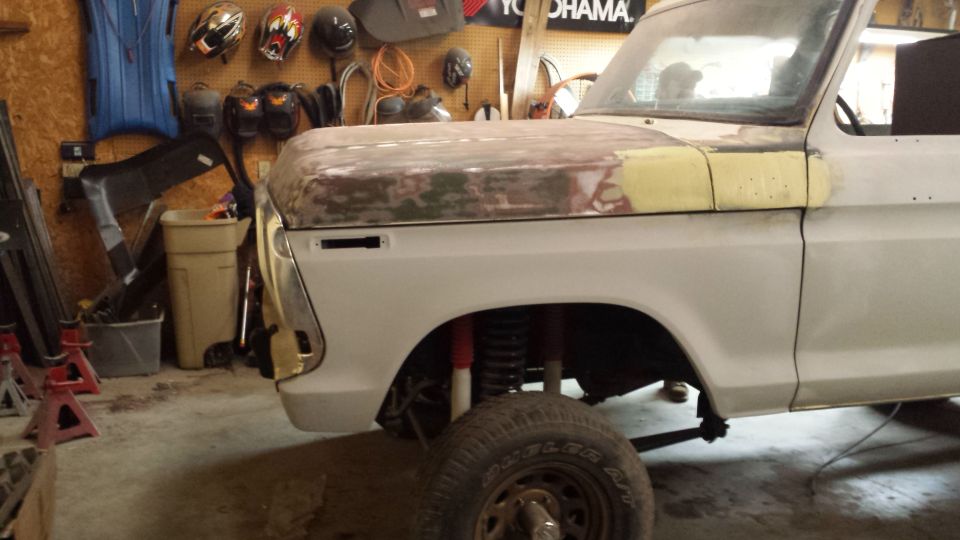 Front fender and hood of a 1978 Ford Bronco in a garage, undergoing repairs