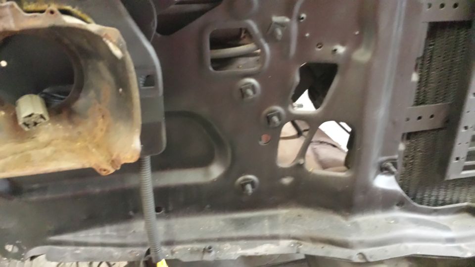Close-up of a vehicle's inner fender area, showing rusty metal and mounting points