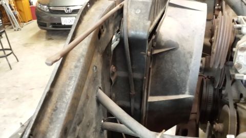 1978 Ford Bronco - The photo shows engine components, including the radiator fan and drive belts, with a car in the background.