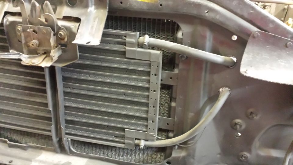 Radiator and condenser assembly with hoses and hood latch mechanism