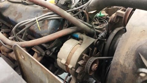 1978 Ford Bronco - The engine bay is filled with hoses, wires, and the alternator, suggesting a complex mechanical system.