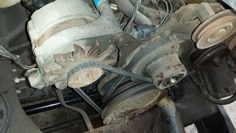 Close-up of engine belts and pulleys, showing wear and tear