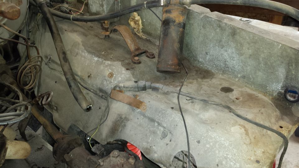 Engine bay with hoses, wires, and rusty metal brackets