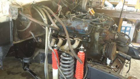 1978 Ford Bronco - The engine bay of a vehicle is shown with its V8 engine partially disassembled, revealing suspension components and wiring.