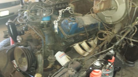 1978 Ford Bronco - Close-up view of a vehicle's engine bay, showing blue valve covers and exhaust manifolds.