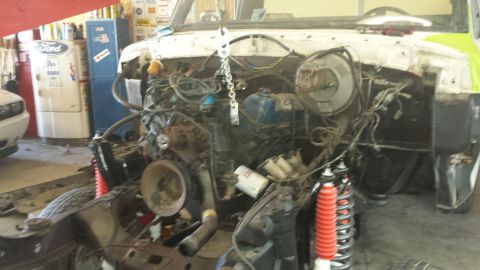 1978 Ford Bronco - The engine bay of a white vehicle is shown with the engine removed, revealing the chassis and suspension.