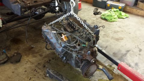 1978 Ford Bronco - Engine removed from vehicle, suspended by chain hoist in a workshop setting.