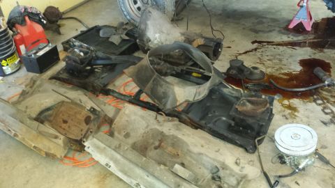 1978 Ford Bronco - Various disassembled vehicle parts, including a radiator and transmission, are laid out on a concrete floor, suggesting a repair or restora…