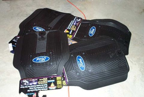 1998 Ford Crown Victoria - A collection of black Ford-branded rubber floor mats are shown, some with their original packaging attached.