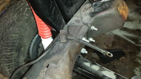 1978 Ford Bronco - Close-up view of the front suspension and frame of a 1978 Ford Bronco, a red shock absorber boot.