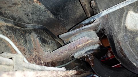 1978 Ford Bronco - This image shows a close-up view of a rusty suspension component, likely from the undercarriage of a vehicle, with visible cobwebs.