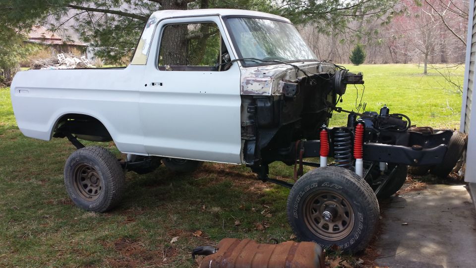 1978 Ford Bronco body with front end removed, undergoing restoration. Red shocks visible