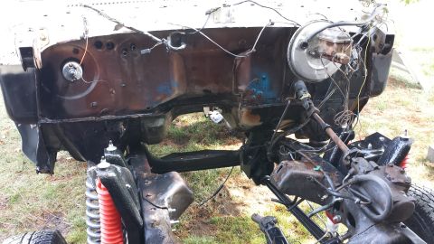 1978 Ford Bronco - The front end of a vehicle is disassembled, showing the frame and engine bay components.