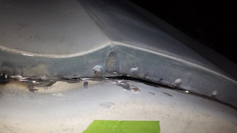 1978 Ford Bronco - Close-up of a damaged metal panel seam with rivets and rust, suggesting repair work on a vehicle part.