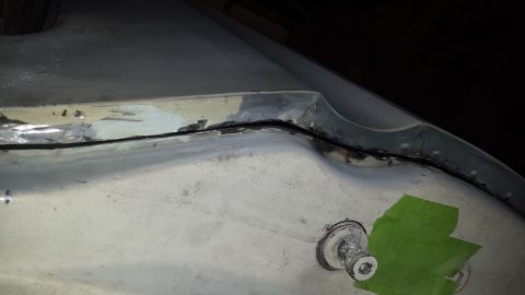 1978 Ford Bronco - Close-up view of a damaged vehicle body panel seam, partially covered with green tape, showing signs of repair and wear.