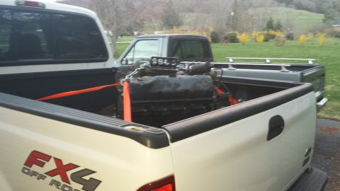 1978 Ford Bronco - Engine being transported in the bed of a pickup truck, with another truck in the background.
