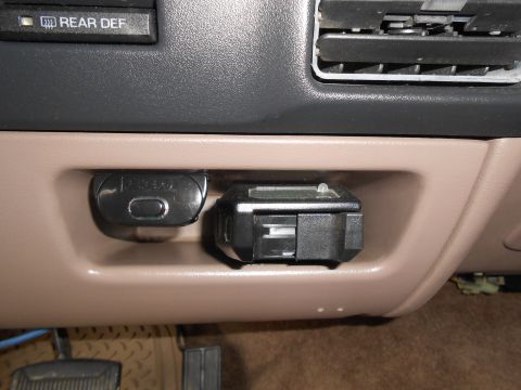 1992 Ford Bronco - Close-up of the trailer brake controller and rear defrost button inside a vehicle's cabin.