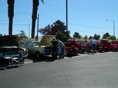 1979 Ford Bronco - A car show displays various vehicles, including hot rods and a sedan, with their hoods open for viewing.