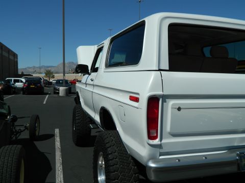 1979 Ford Bronco - White Ford Bronco with lifted suspension parked in a lot, other vehicles visible.
