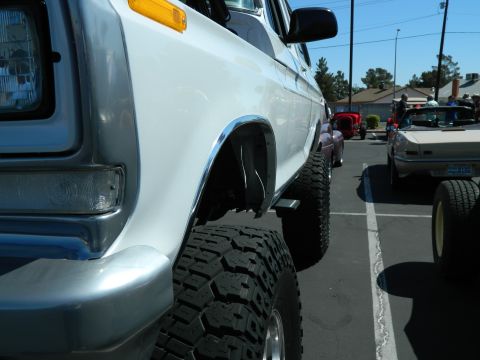 1979 Ford Bronco - A lifted white pickup truck is parked in a lot with other vehicles visible in the background.