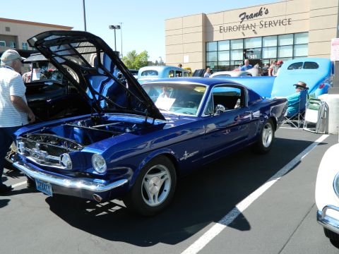 1979 Ford Bronco - A blue 1965 Ford Mustang coupe is displayed with its hood open at an outdoor car show.