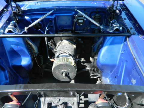 1979 Ford Bronco - The engine bay of a blue vehicle, a large motor and structural bracing.