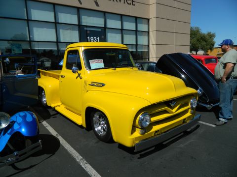 1979 Ford Bronco - A bright yellow 1956 Ford F-100 pickup truck is parked outside a building with other cars.