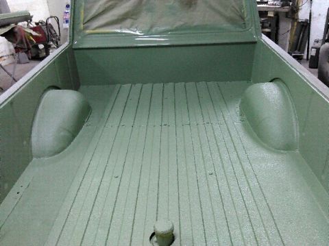 1960 Ford Ranchero - The interior of a 1960 Ford Ranchero truck bed, freshly painted green, shows its ribbed floor and wheel wells.