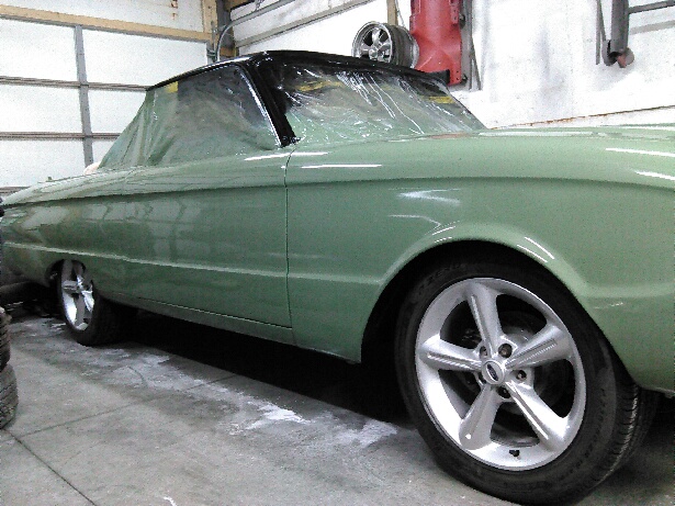 Green convertible car with plastic sheeting over the roof and windows, custom wheels, side view