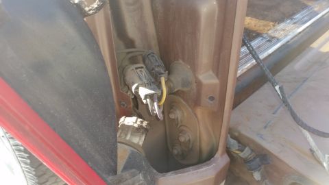 1985 Ford Bronco - Electrical connectors and wiring harness visible within a vehicle's body panel, likely for a light or sensor.