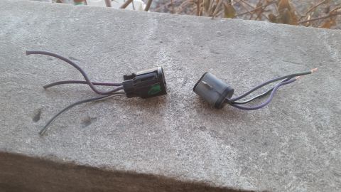 1985 Ford Bronco - Two electrical connectors with wires are shown resting on a concrete ledge outdoors.