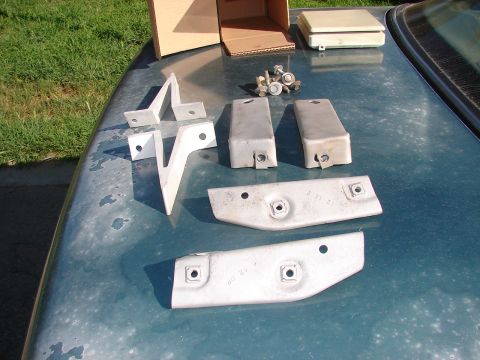 1973 Ford Ranchero - Several metal car parts and fasteners are displayed on the hood of a teal vehicle.