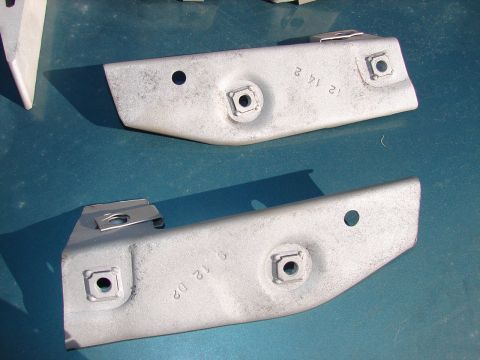 1973 Ford Ranchero - Close-up of two metal automotive brackets with stamped date codes visible.