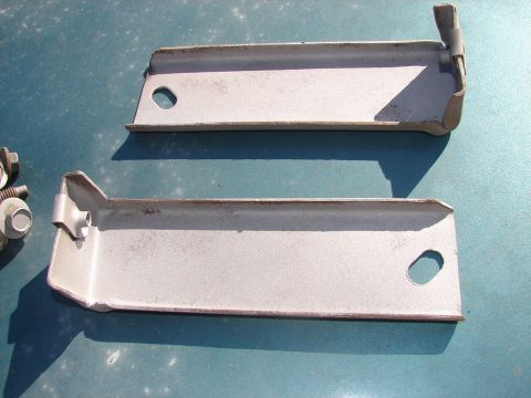 1973 Ford Ranchero - Two metal brackets and bolts are shown on a teal surface.
