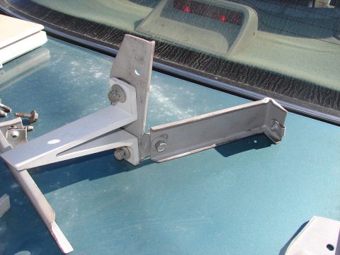 1973 Ford Ranchero - A metal bracket assembly is shown on the hood of a teal-colored vehicle, positioned near the rear window.