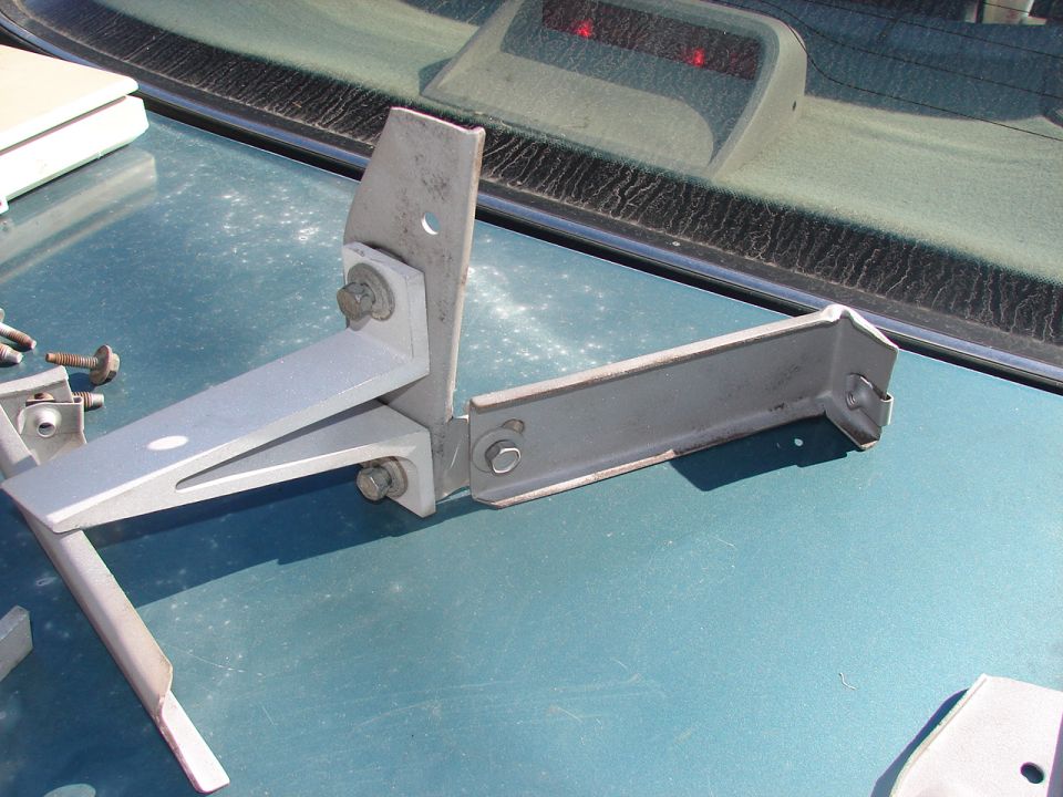 Metal bracket assembly on teal car hood, near rear window