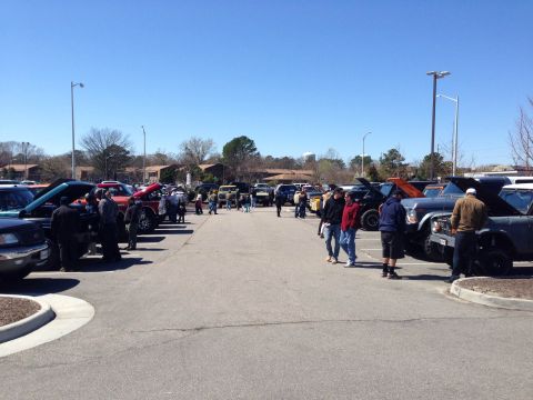 1979 Ford Bronco - A gathering of vehicles and people in a parking lot on a sunny day.