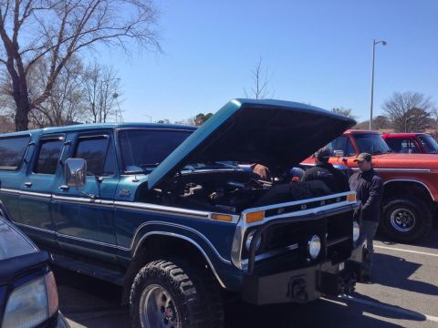 1979 Ford Bronco - Blue Ford Bronco SUV with hood open, parked next to an orange Ford truck.