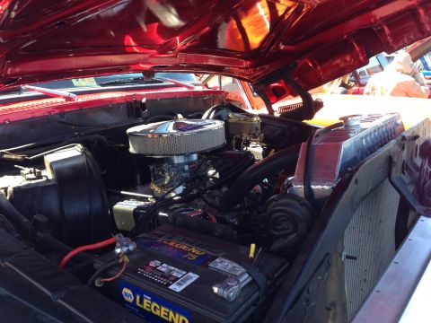1979 Ford Bronco - Close-up view of a red vehicle's engine bay, showing the air filter, carburetor, and battery.