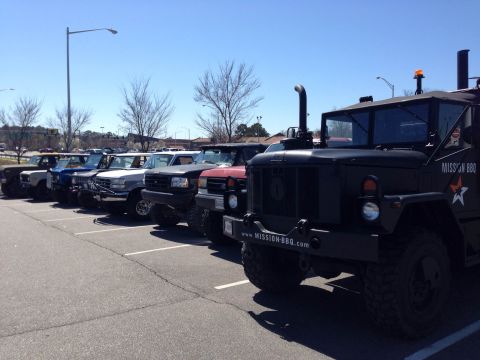 1979 Ford Bronco - Multiple trucks and SUVs are parked in a lot on a sunny day.