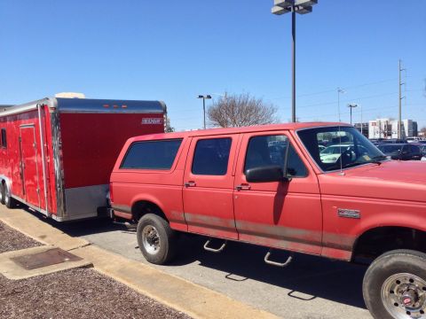 1979 Ford Bronco - A red SUV is parked and hitched to a red trailer on a sunny day.