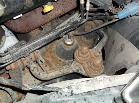 1999 Mercury Grand Marquis - Close-up view of engine and suspension components, showing signs of rust and various wires and hoses.