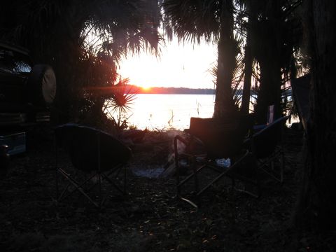 1994 Ford Bronco - A sunset scene with palm trees and camping chairs set up by the water.