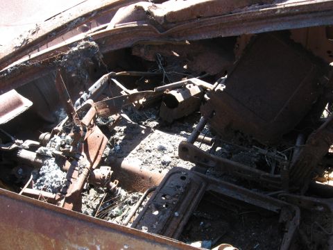 1994 Ford Bronco - The interior of a vehicle is heavily damaged and rusted, with debris scattered throughout.