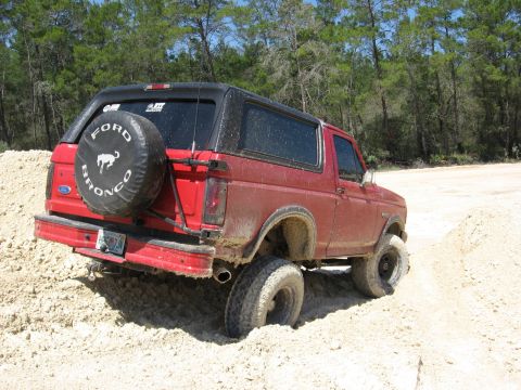 1994 Ford Bronco - Red Ford Bronco is stuck in the sand off-road.