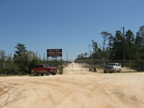 1994 Ford Bronco - Two SUVs are parked near the entrance gate of the U.S. Navy Bombing Range on a sunny day.