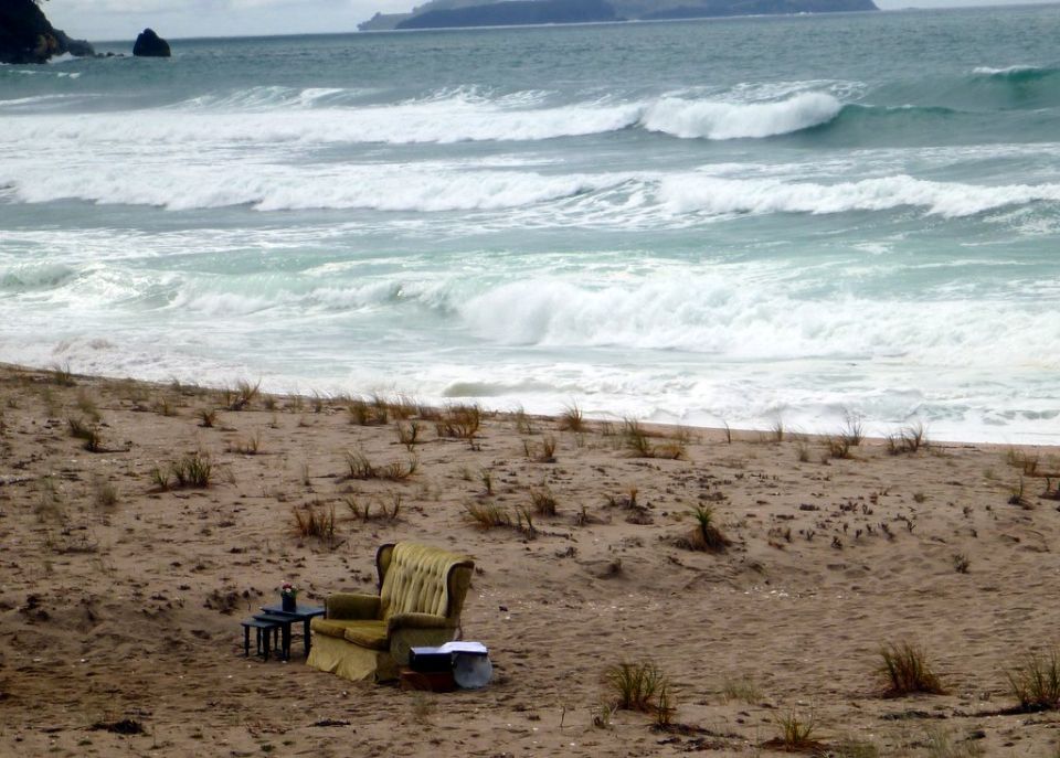 Armchair and side table on a sandy beach with ocean waves
